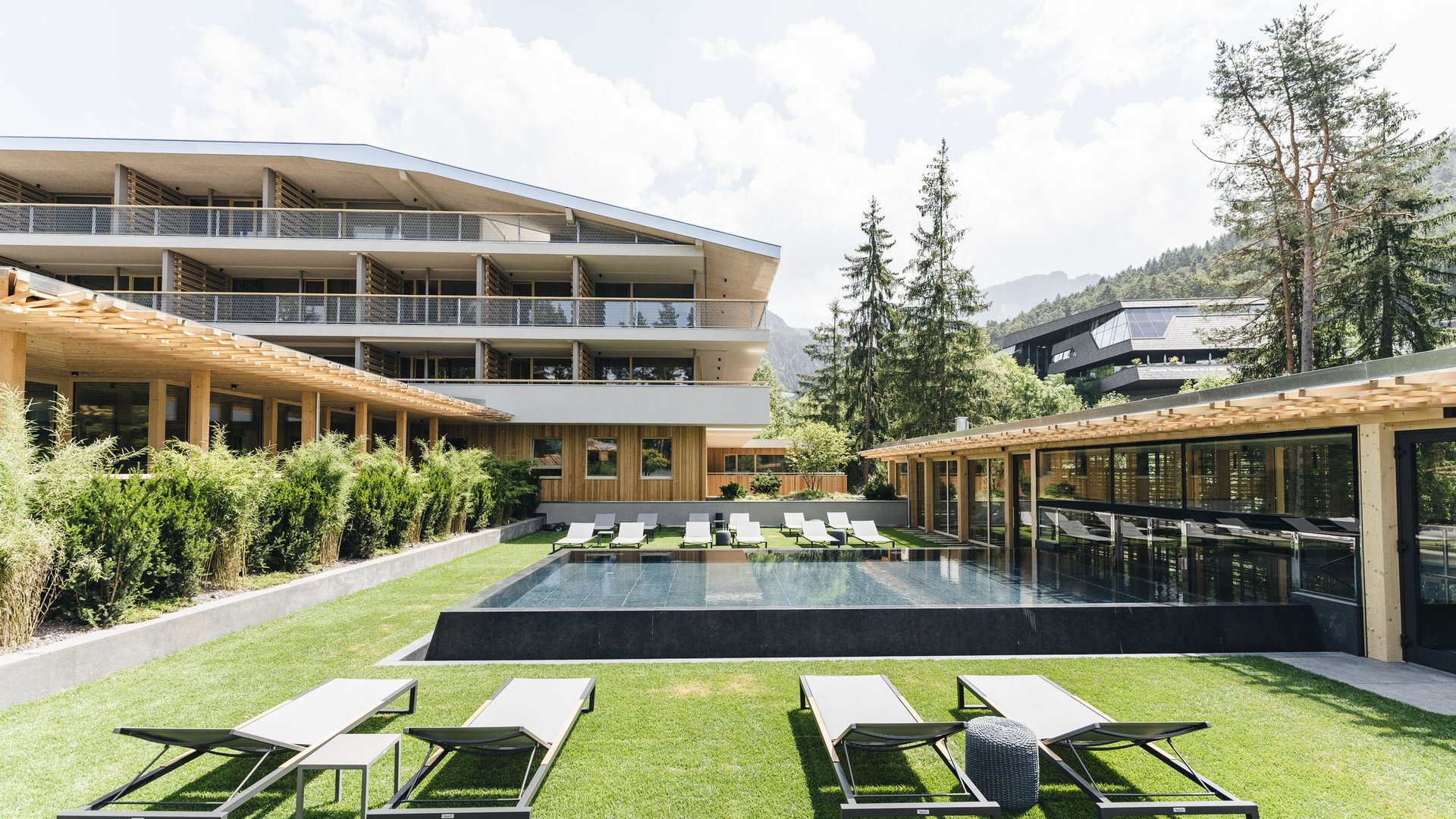 Sensoria Dolomites – Luxury for the Soul Modern hotel garden with lounge chairs and a square water pool