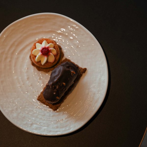 Sensoria Dolomites – Luxury for the Soul Two small pastries on a white plate on a dark table