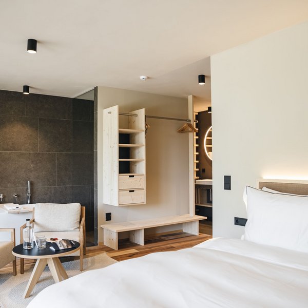 Sensoria Dolomites. Kraftort. Winterzauber. Modernes Hotelzimmer mit Doppelbett, Sitzecke und Badewanne
