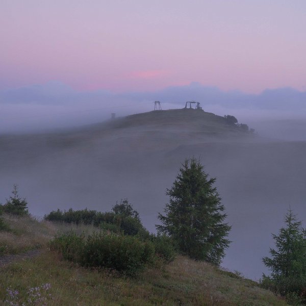 Sensoria Dolomites – Luxury for the Soul Nebeliger Hügel mit Bäumen und Seilbahn im sanften Morgenlicht