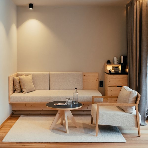 Sensoria Dolomites – Luxury for the Soul Modern living room with sofa, armchair, table, and glass side door