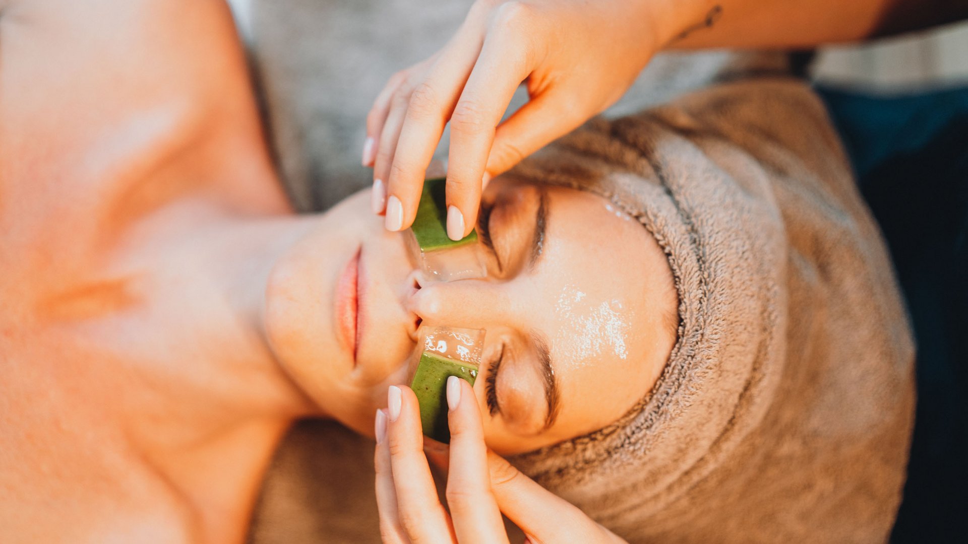 Sensoria Dolomites – Luxury for the Soul Woman receiving facial treatment with aloe vera gel and towel wrapped around head