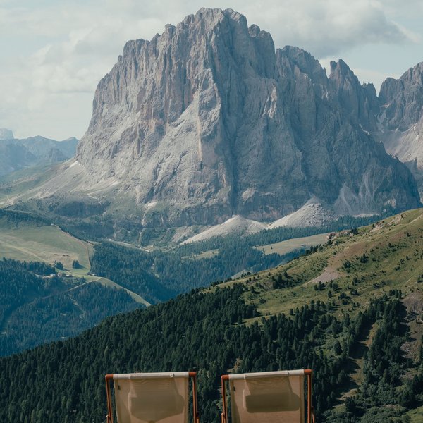 Sensoria Dolomites – Luxury for the Soul Two deck chairs facing a large mountain in a valley on a clear day