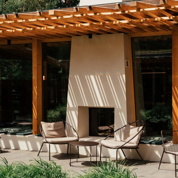 Sensoria Dolomites – Luxury for the Soul Modern outdoor area with fireplace, chairs, and green plants