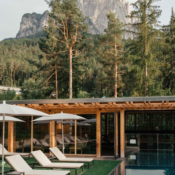 Sensoria Dolomites – Luxury for the Soul Sun loungers and umbrellas by pool with mountain backdrop