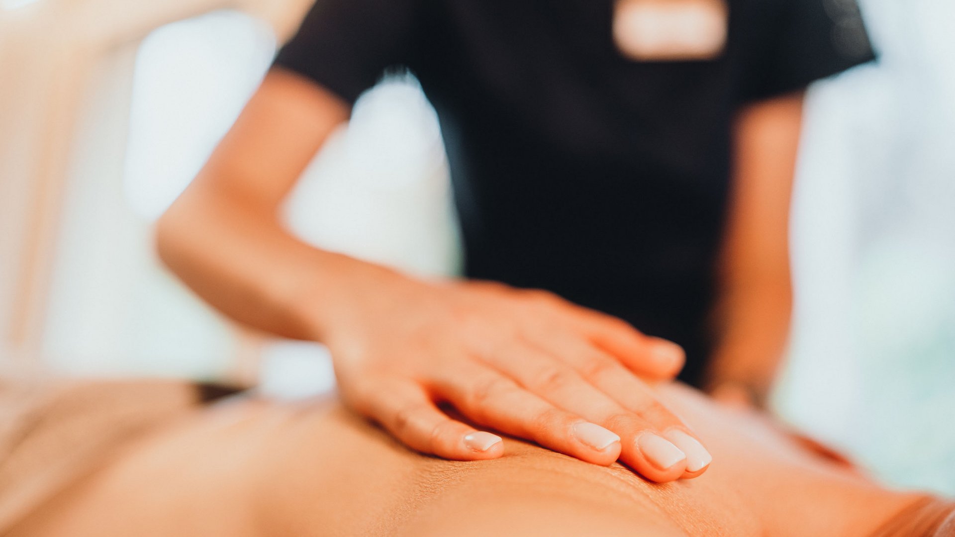 Sensoria Dolomites. Kraftort. Winterzauber. Nahaufnahme einer Hand bei einer wohltuenden Rückenmassage