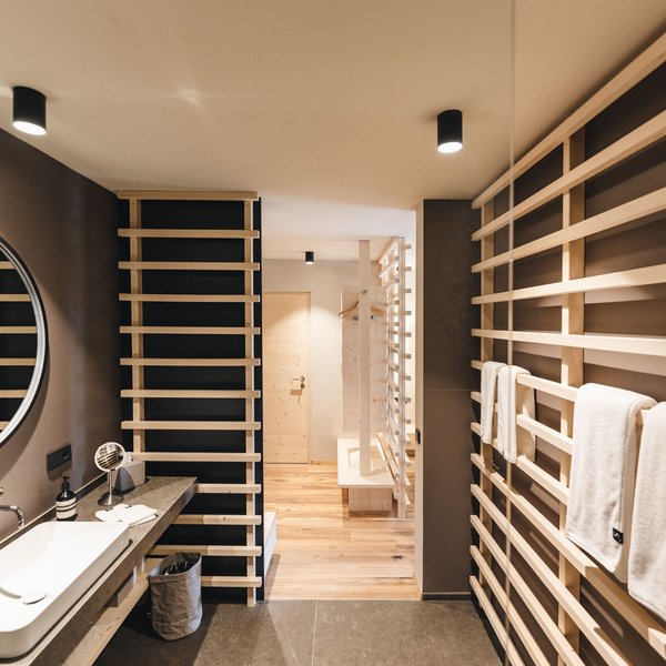 Sensoria Dolomites – Luxury for the Soul Modern hotel bathroom area with wooden panels and hanging towels