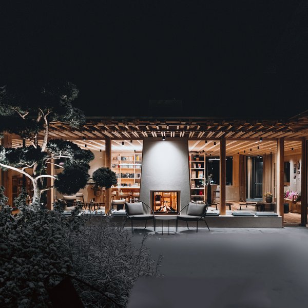 Sensoria Dolomites. Kraftort. Winterzauber. Modern beleuchtetes Haus mit Kamin und Außensitzbereich bei Nacht