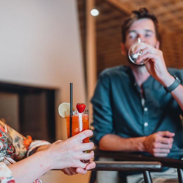 Sensoria Dolomites – Luxury for the Soul Woman holding cocktail and man drinking beverage in cozy setting