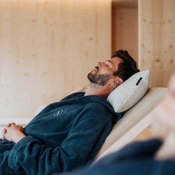 Sensoria Dolomites – Luxury for the Soul Man relaxing in bathrobe on lounge chair with pillow at spa