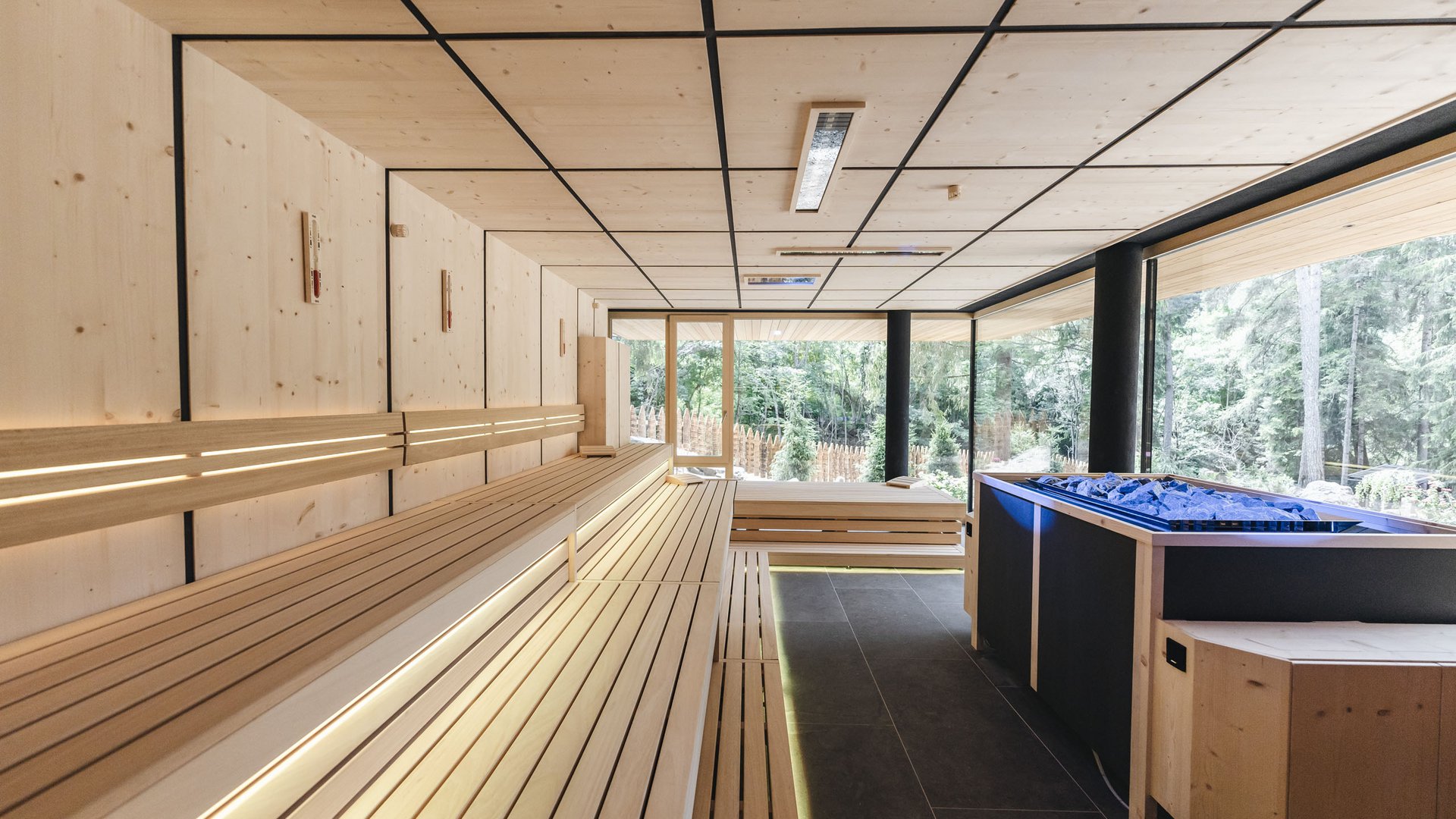 Sensoria Dolomites – Luxury for the Soul Modern wooden sauna room with forest view and sauna heater