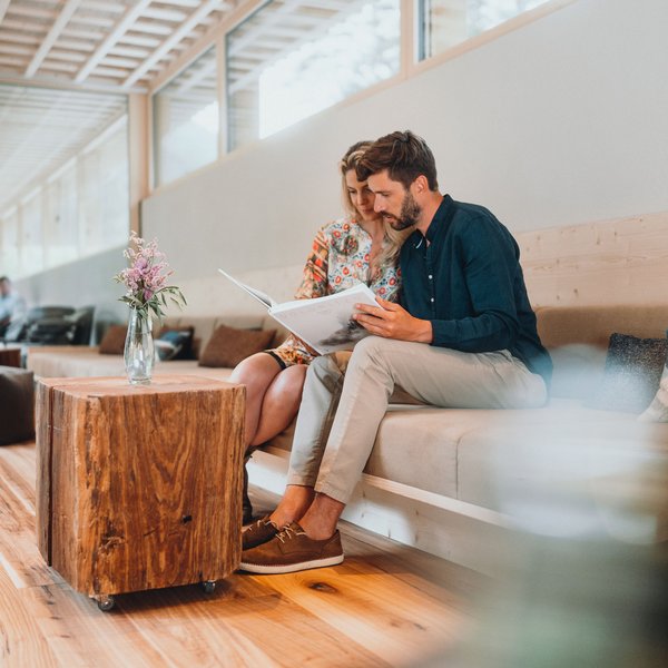 Sensoria Dolomites – Luxury for the Soul Couple sitting and reading a book together in a modern living room