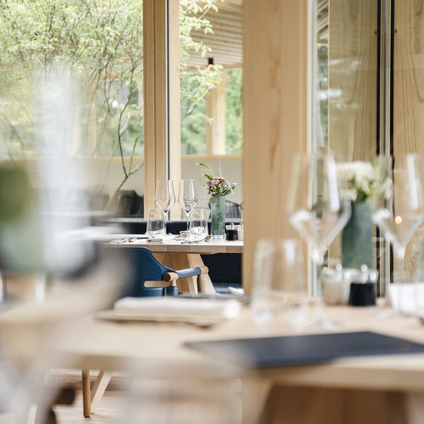 Sensoria Dolomites – Luxury for the Soul View of set tables in a modern restaurant with wood accents and floral decorations